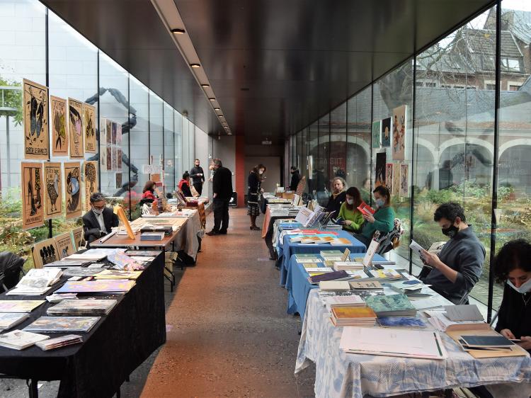 tables avec livres de part et d'autre d'un couloir vitré