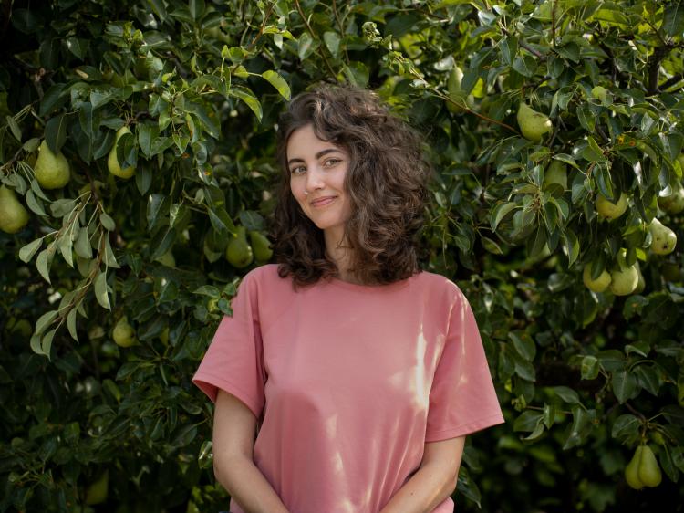 femme avec cheveux bouclés bruns penchant la tête sur le côté devant poiriers