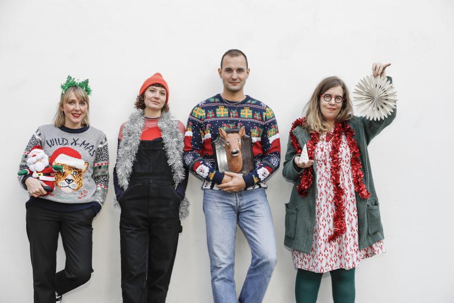 4 personnes en habits de Noël adossées à un mur blanc