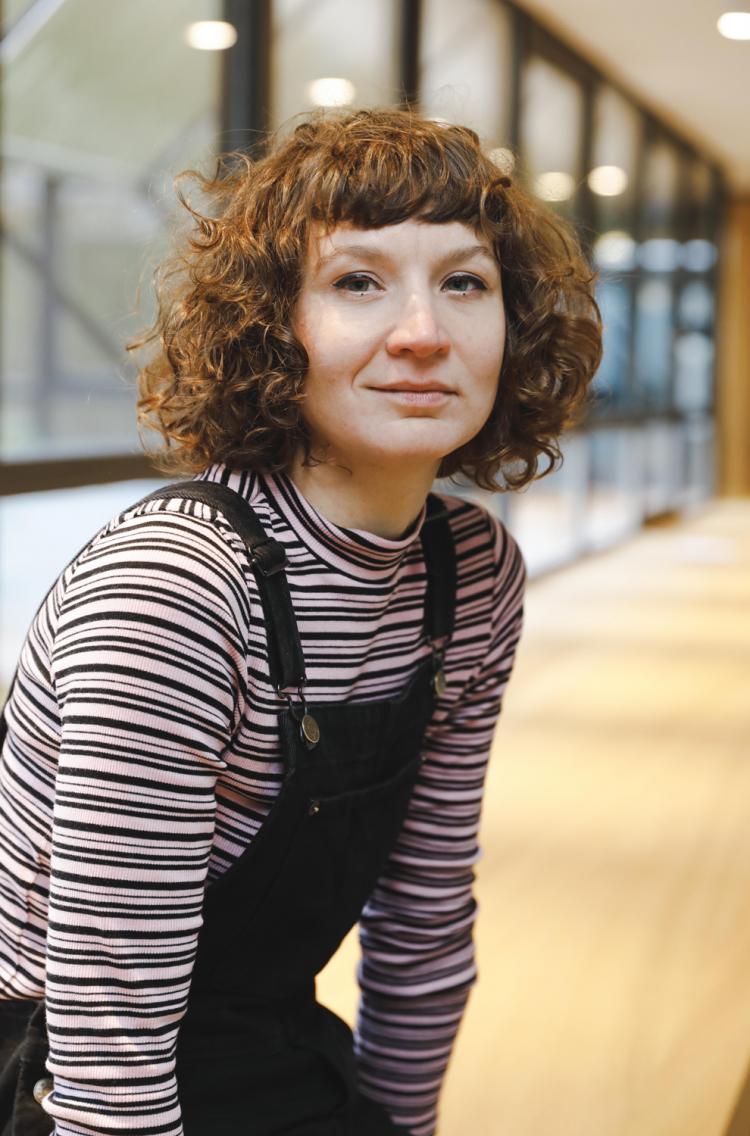 femme bouclée brune avec un sous-pull à ligne et une salopette noire