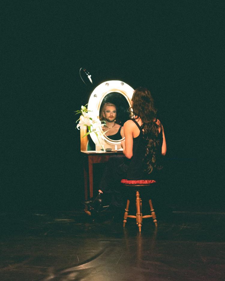 femme avec barbe qui se maquille devant un psyché sur scène