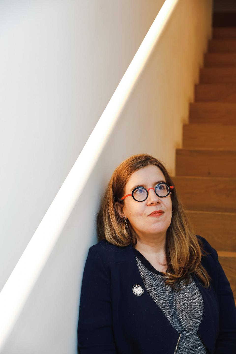 femme appuyée sur un escalier avec des lunettes rouge et noir